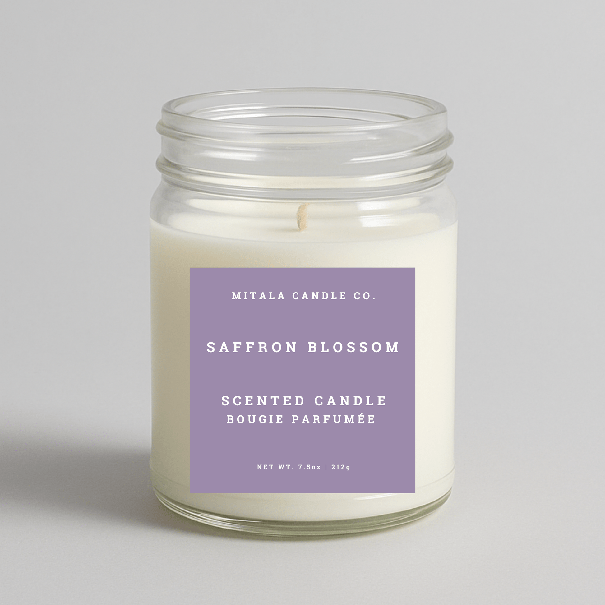 Mitala Candle Co. Saffron Blossom scented candle in a glass jar with a purple label on a light gray background
