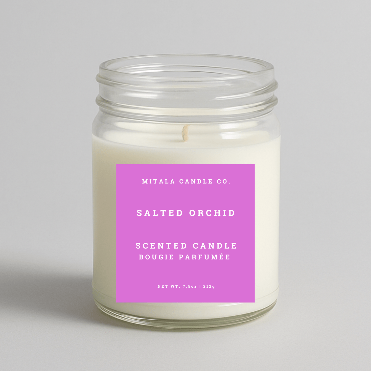 Mitala Candle Co. salted orchid scented candle with a pink label on a light gray background