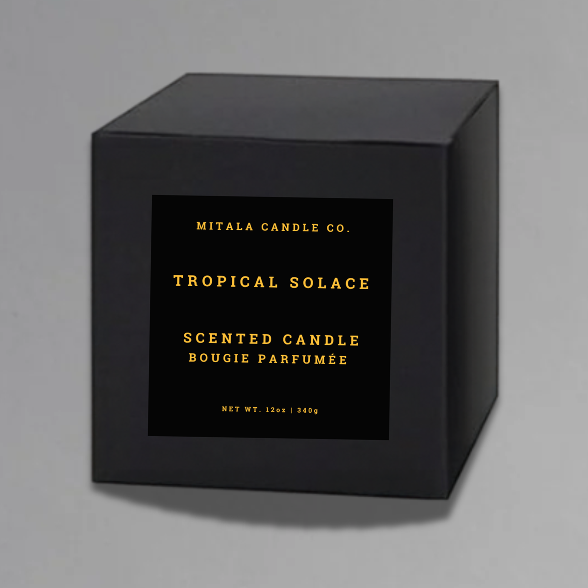 Luxury 12oz soy candle 'Tropical Solace' by Mitala Candle Co. next to white gift box on gray background