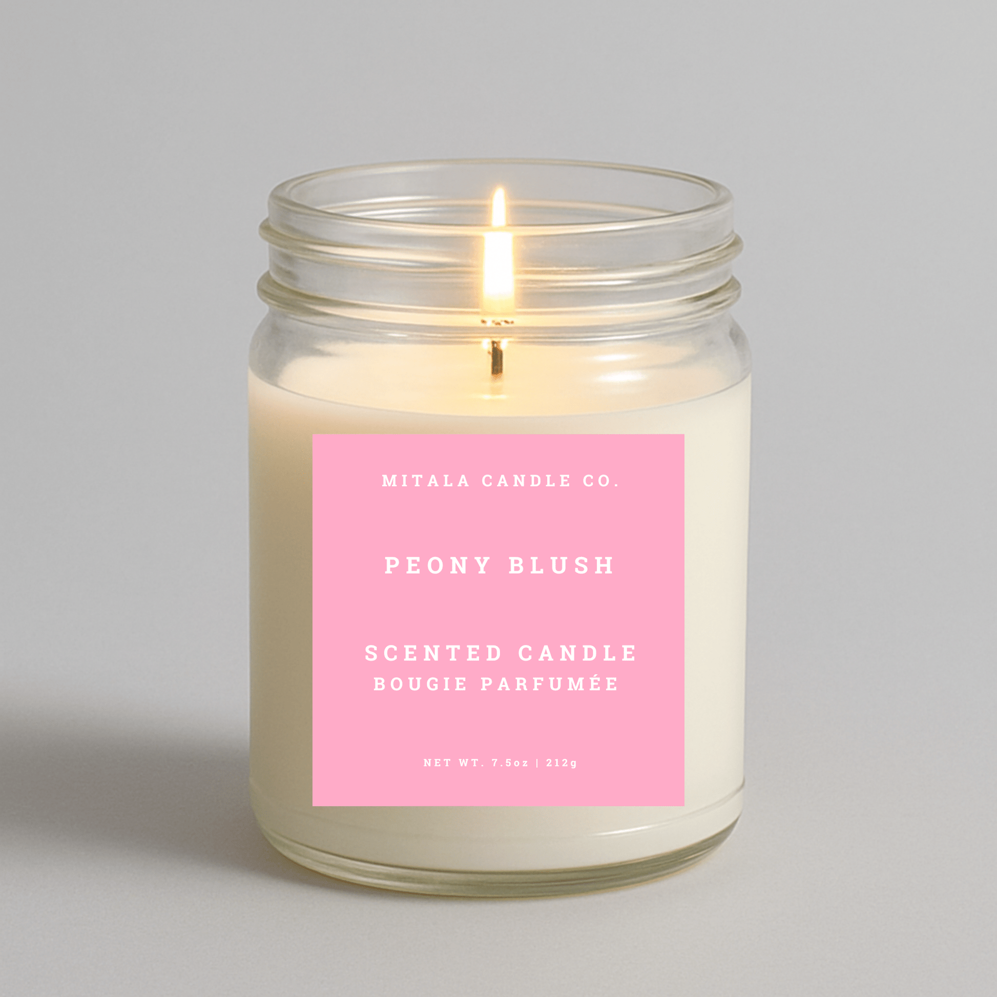 Mitala Candle Co. peony blush scented candle with a pink label on a gray background