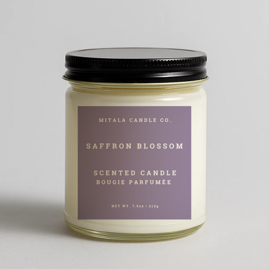 Mitala Candle Co. Saffron Blossom scented candle with purple label and black lid, 7.5oz, light gray background