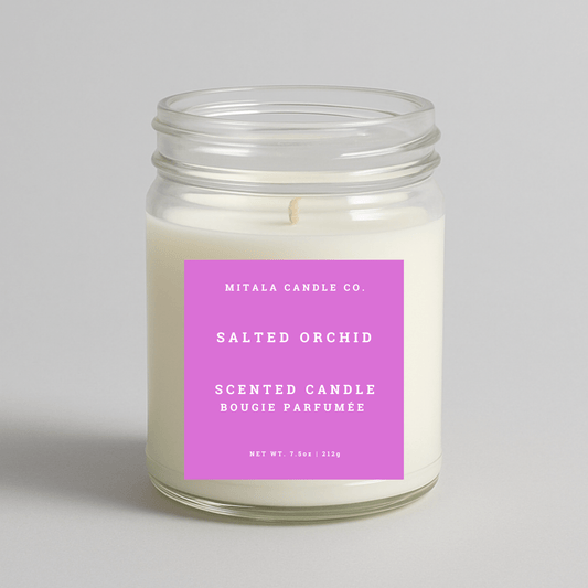 Mitala Candle Co. salted orchid scented candle with a pink label on a light gray background