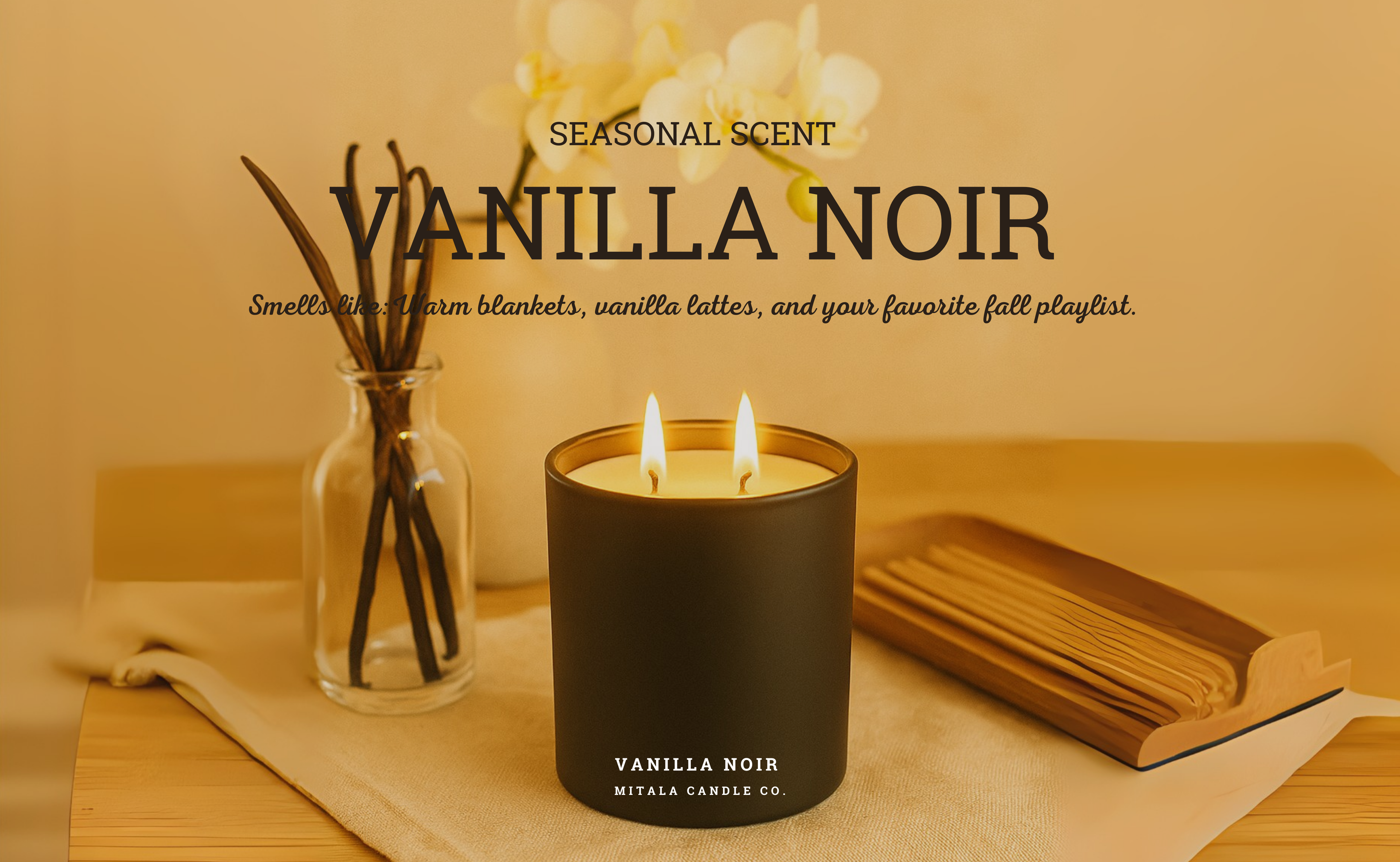 A Mitala Candle Co. candle  in a black jar labeled "Vanilla Noir" is lit on a wooden table beside a jar with sticks and an open book. The scene is warm and inviting. Text reads: "Seasonal Scent, Vanilla Noir. Smells like: Warm blankets, vanilla lattes, and your favorite fall playlist."
