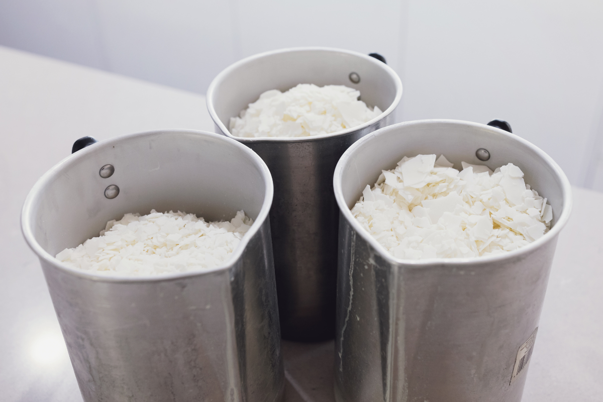 Three metal pails filled with shredded or grated cheese are placed on a light-colored countertop. The buckets are closely grouped together.