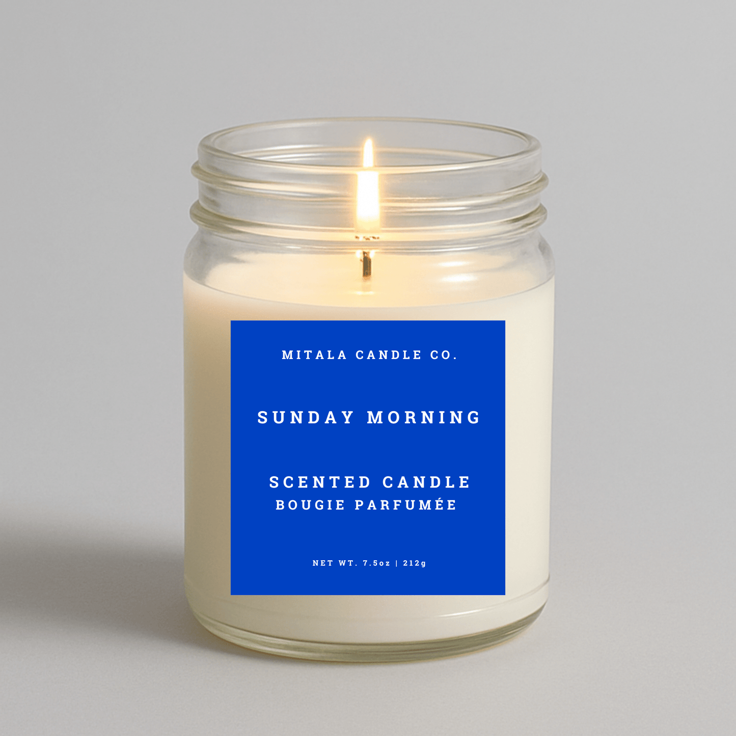 7.5oz Sunday Morning scented candle by Mitala Candle Co. with blue label on gray background, perfect for gifts or home decor