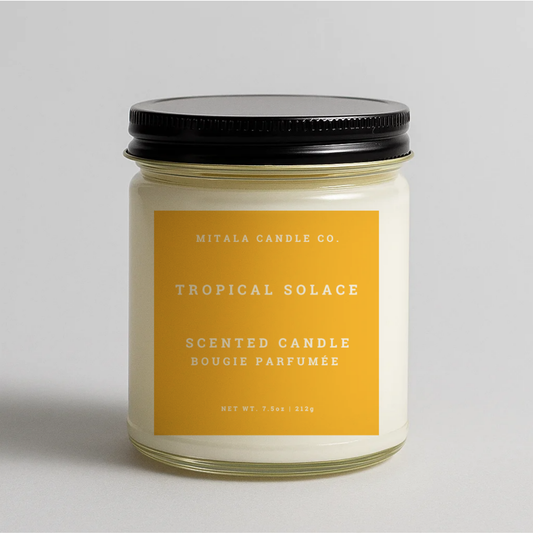 Mitala Candle Co. Tropical Solace candle with yellow label and black lid, 7.5oz, gray background