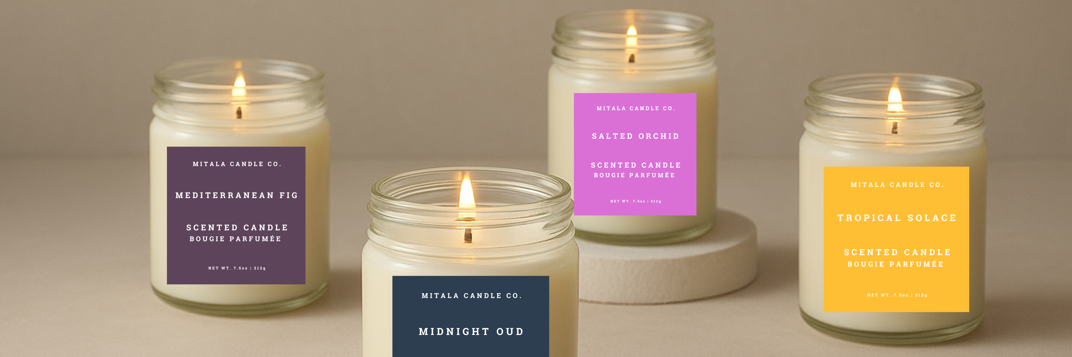 Four Mitala Candle Co. lit candles with labeled jars on a neutral background